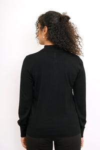 Back view of a woman wearing a black merino wool cardigan sweater showing ribbed hem construction.