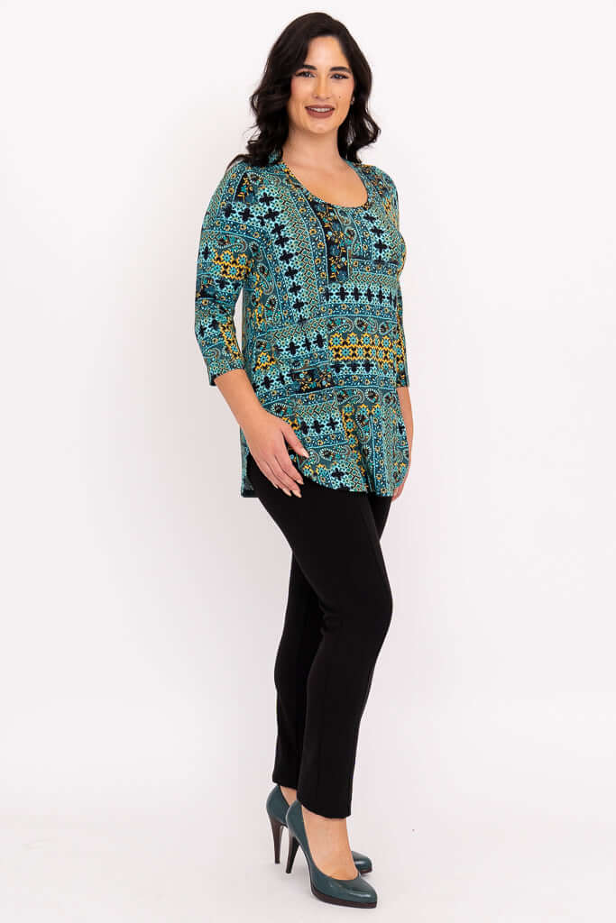 Side view of woman in turquoise and gold patterned 3/4 sleeve bamboo top with black pants