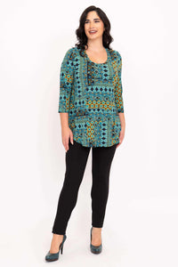 Full front view of model in patterned tunic top, black pants, and teal heels