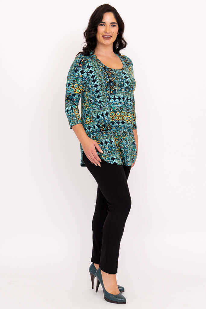 Side view of model in teal and yellow patterned tunic with black pants and teal heels