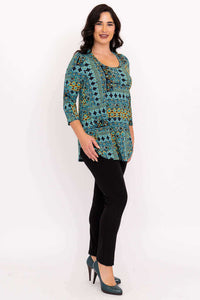 Side view of model in teal and yellow patterned tunic with black pants and teal heels