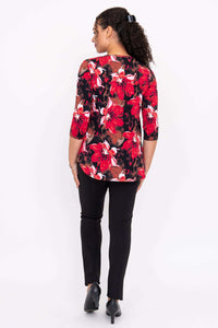 Back view of a woman wearing a red and black floral 3/4 sleeve top and black pants