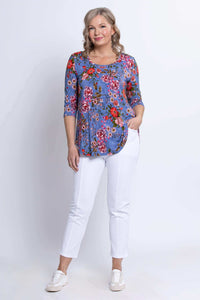 Woman in blue floral 3/4 sleeve top with her hand in the pocket, standing