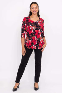 Woman standing in red floral print 3/4 sleeve top, black pants, and black heels