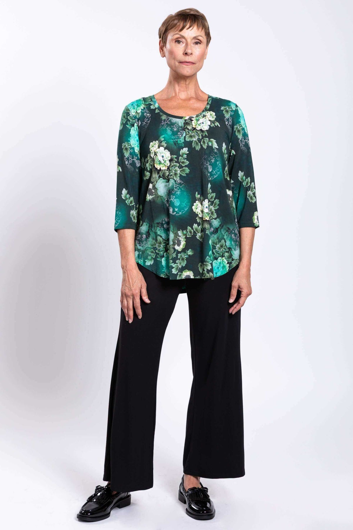 Front view of woman standing confidently in green floral 3/4 bamboo top