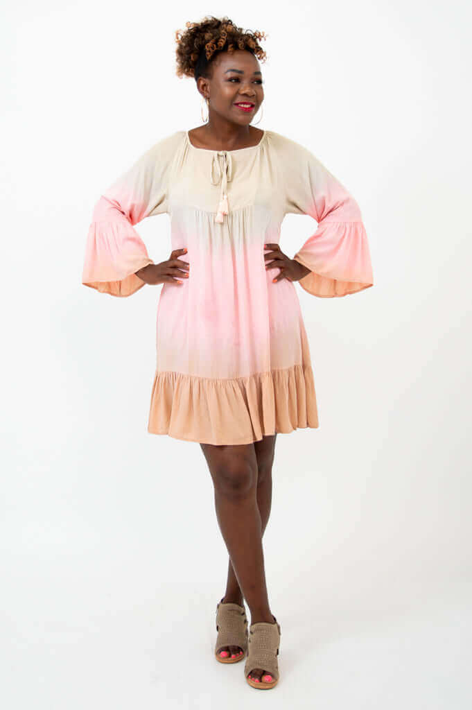Woman modeling a flowy ombre dress with 3/4 ruffle sleeves and tassel neck tie