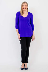 Full body front view of woman in purple V-neck bamboo top and black dress pants