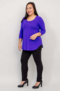 Woman in a purple 3/4 sleeve bamboo top and black pants, standing at an angle.