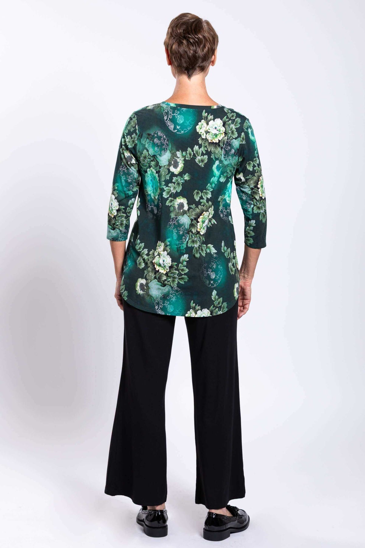 Back view of woman in green floral 3/4 sleeve bamboo top showing hemline
