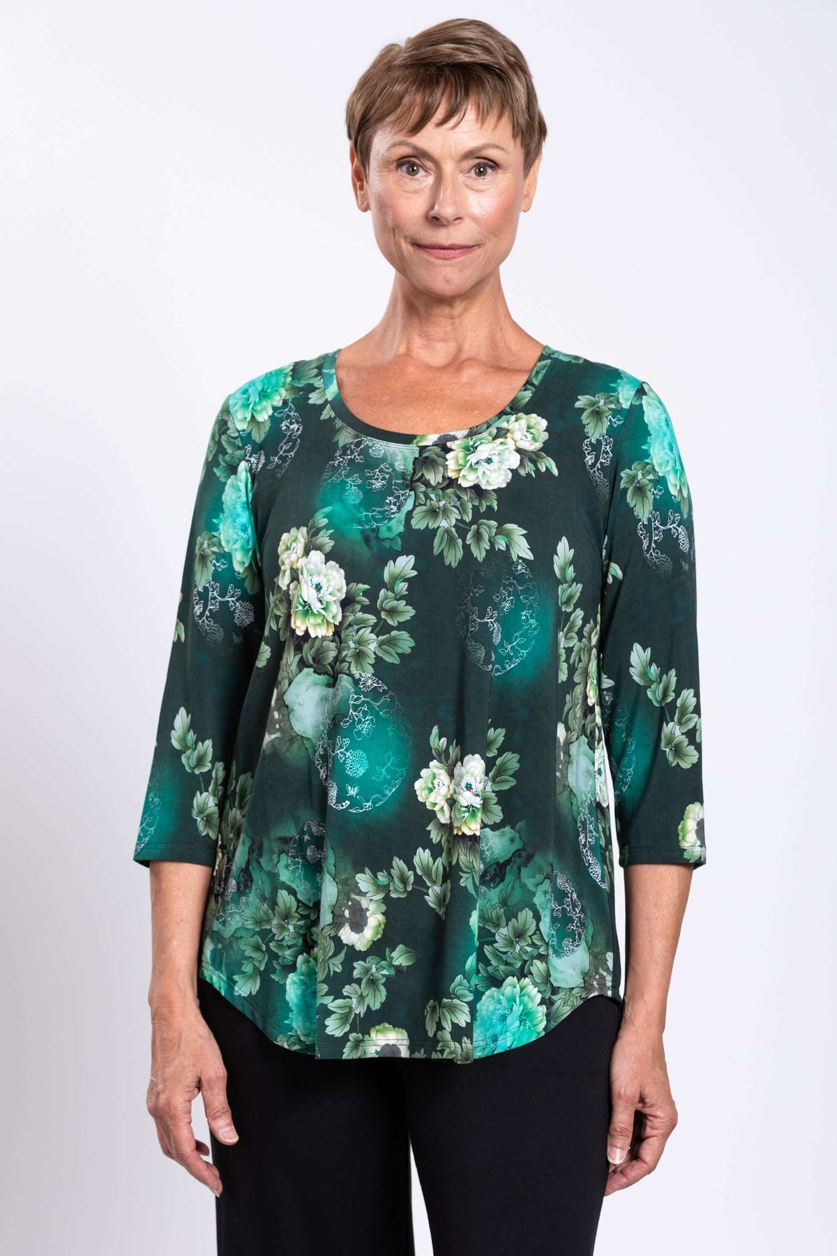 Front view close-up of a woman wearing a green floral 3/4 sleeve bamboo top