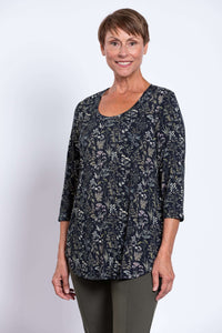 Woman turned slightly to side in black floral 3/4 sleeve top and olive pants