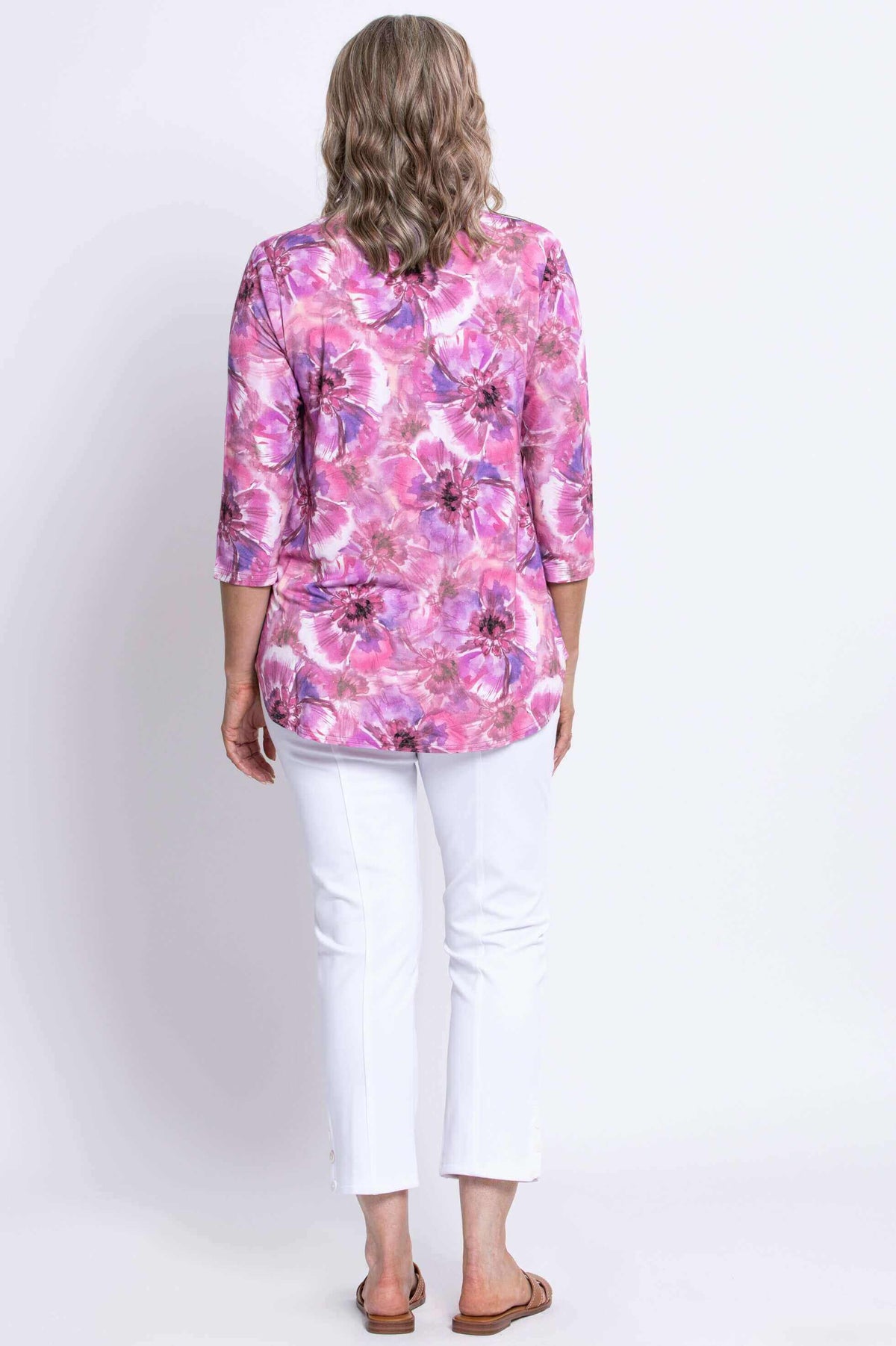 Back view of woman wearing pink and purple floral bamboo top with white pants