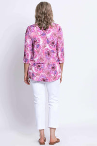 Back view of woman wearing pink and purple floral bamboo top with white pants