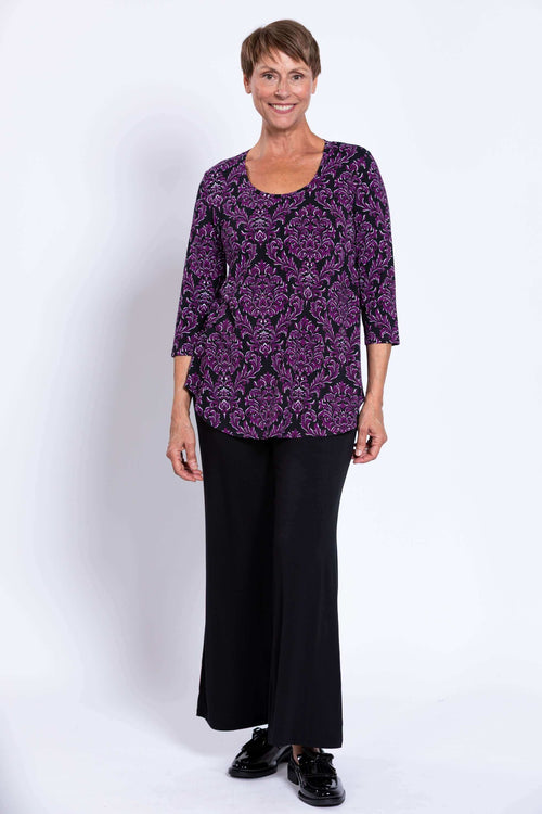 Woman wearing a purple damask Jazz 3/4 sleeve bamboo top with black pants, front view