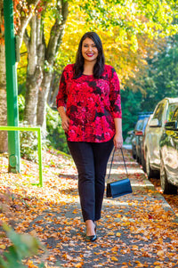 Woman wearing fuchsia swirl 3/4 sleeve bamboo top walking on a leaf-covered sidewalk