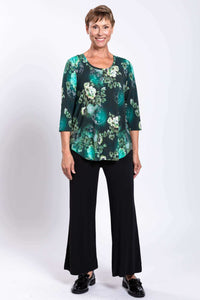 Full front view of woman wearing green floral 3/4 sleeve bamboo top with black pants