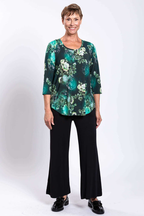 Full front view of woman wearing green floral 3/4 sleeve bamboo top with black pants