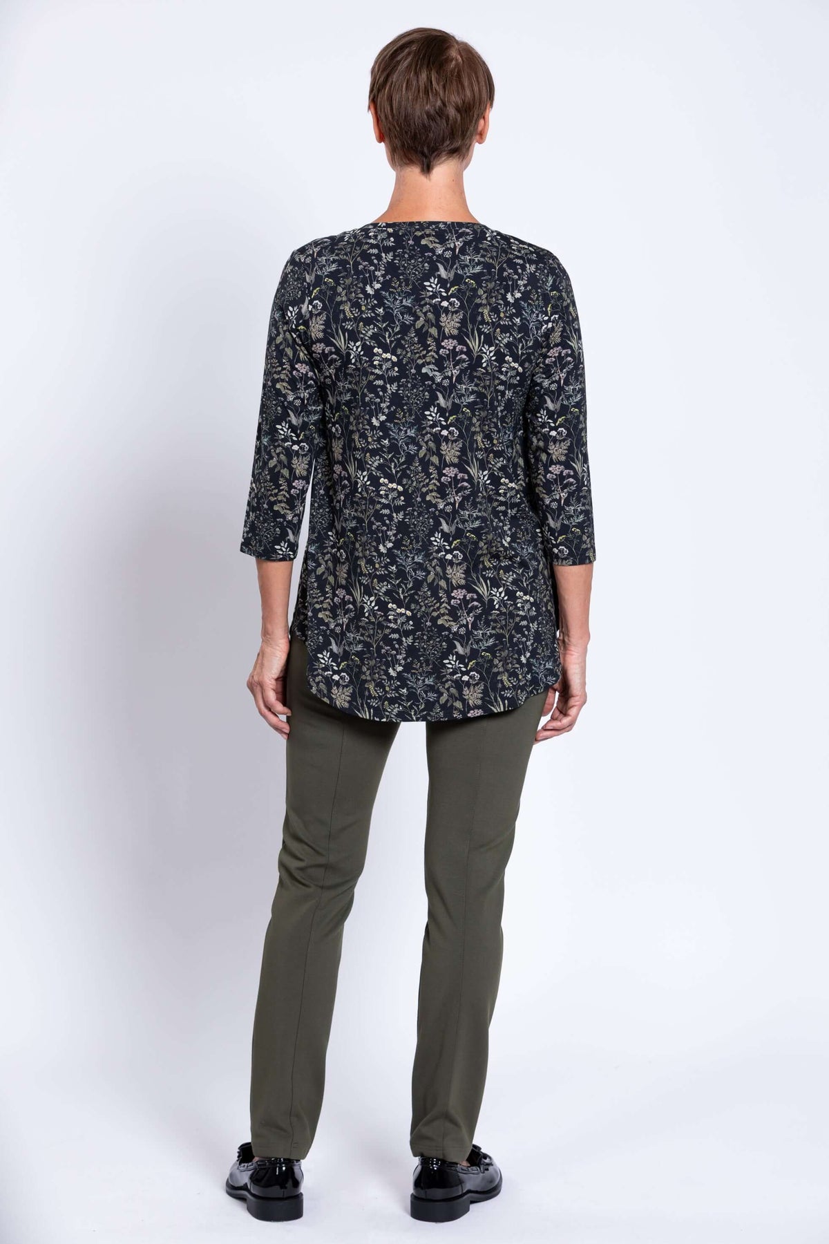 Back view of woman in black floral 3/4 sleeve bamboo top and olive pants
