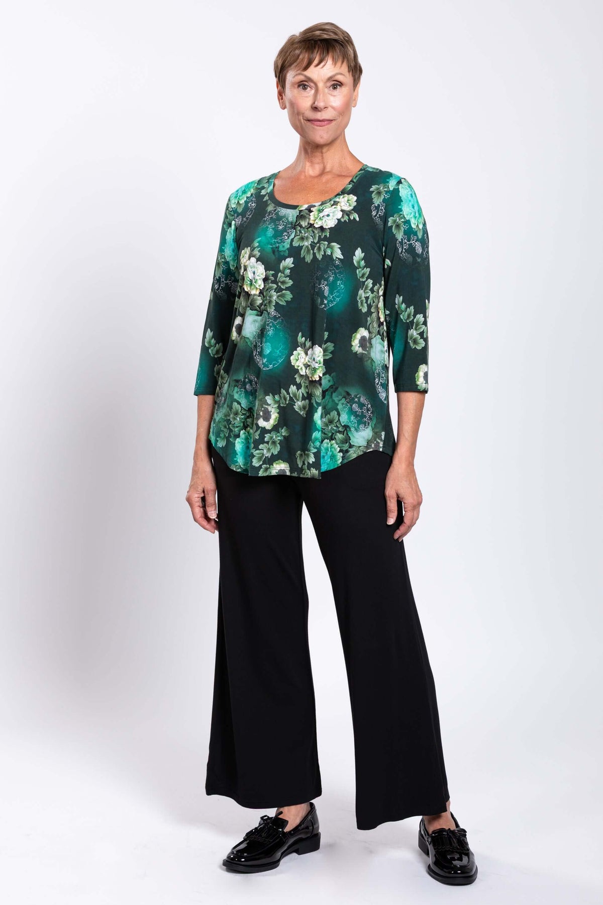Three-quarter angle view of a woman in a green floral 3/4 sleeve bamboo tunic
