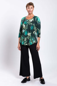 Three-quarter angle view of a woman in a green floral 3/4 sleeve bamboo tunic