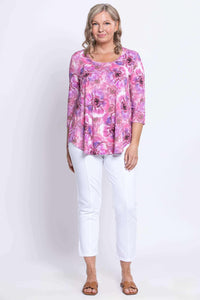 Front view of woman standing in floral 3/4 sleeve bamboo top and white pants