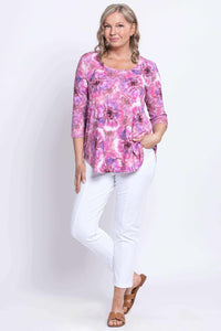 Full body view of woman posing in pink and purple floral 3/4 sleeve bamboo top and white pants