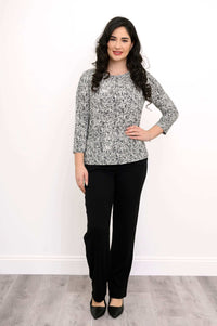 Standing woman in black and white rose print 3/4 sleeve tee with black dress pants