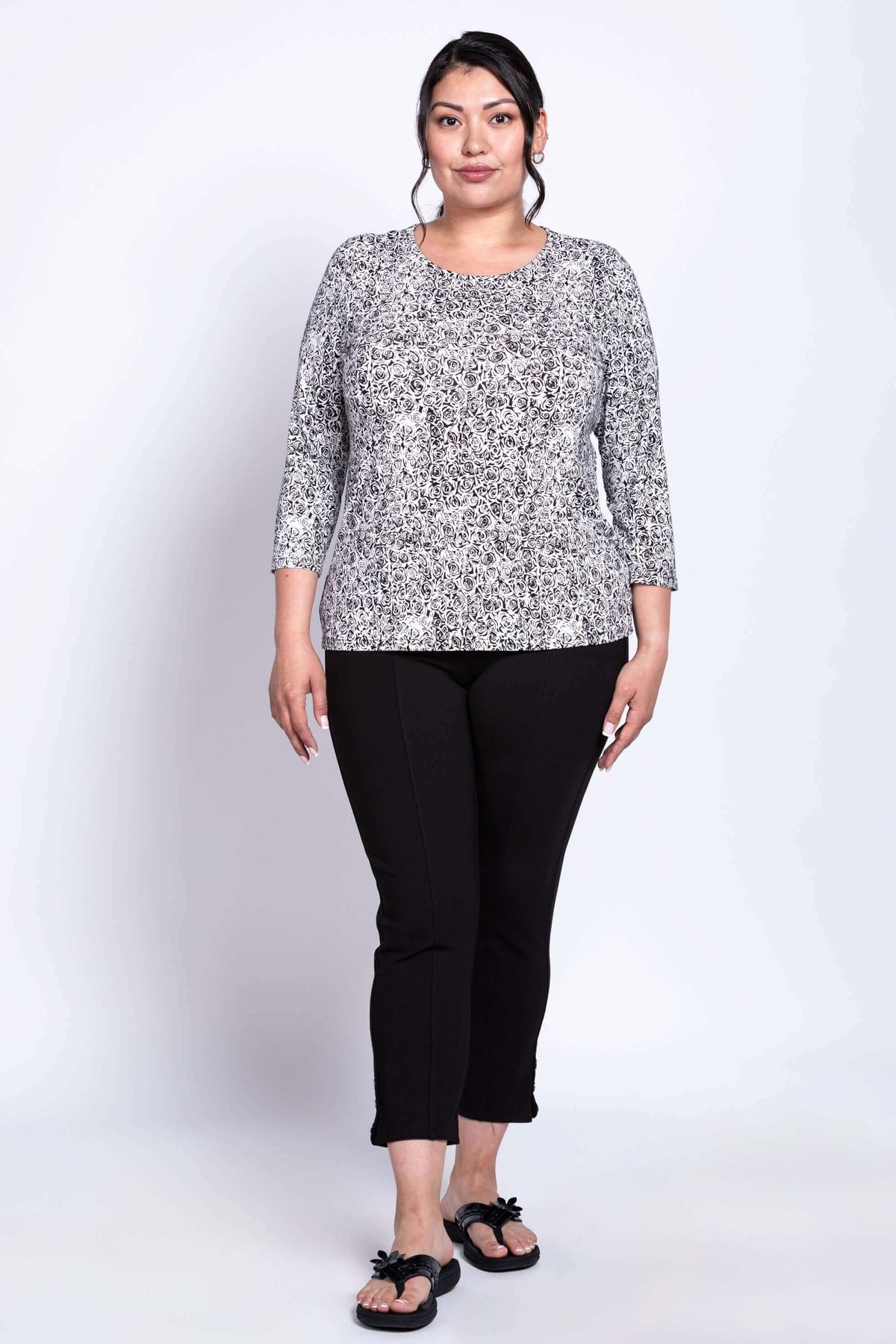 Plus-size woman modeling black and white rose print 3/4 sleeve tee and black pants