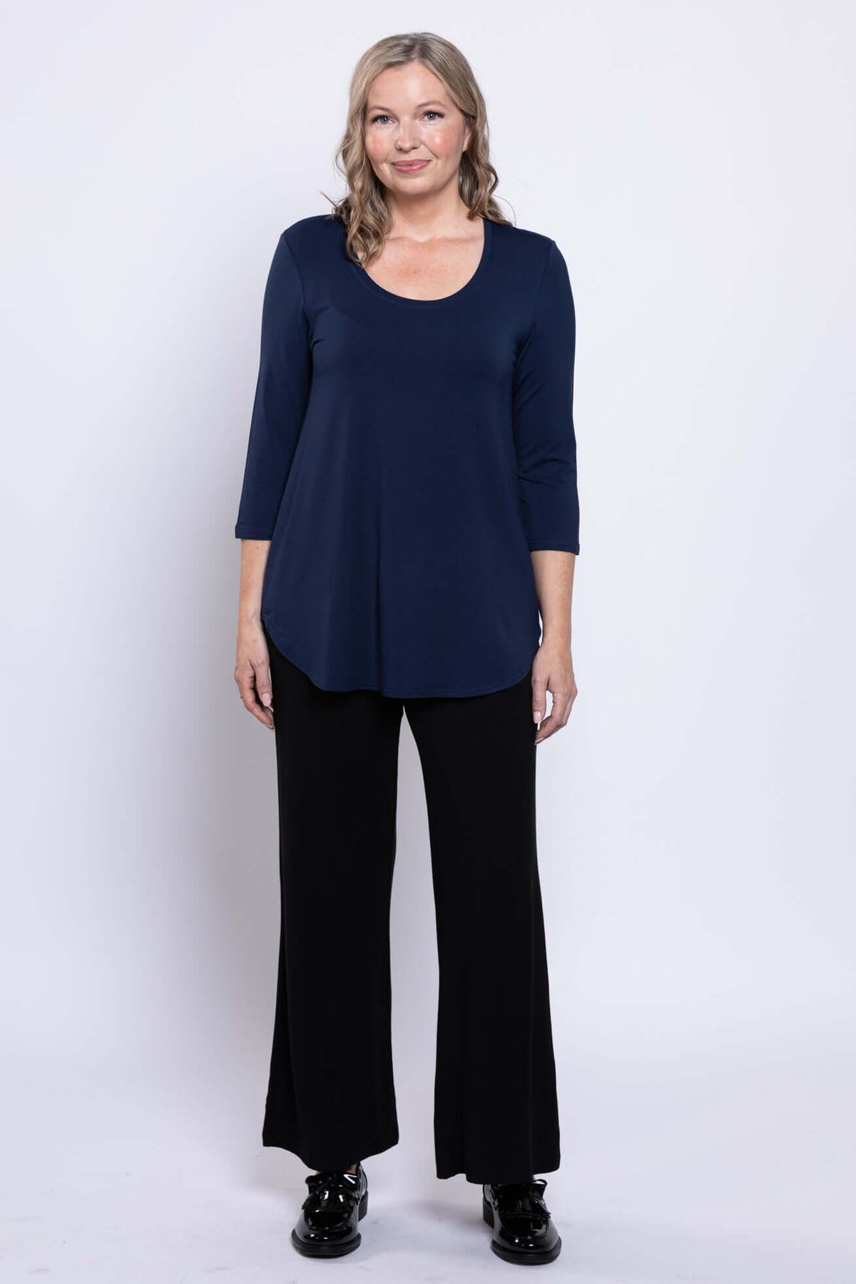 Full front view of a woman in a navy 3/4 sleeve top and black pants
