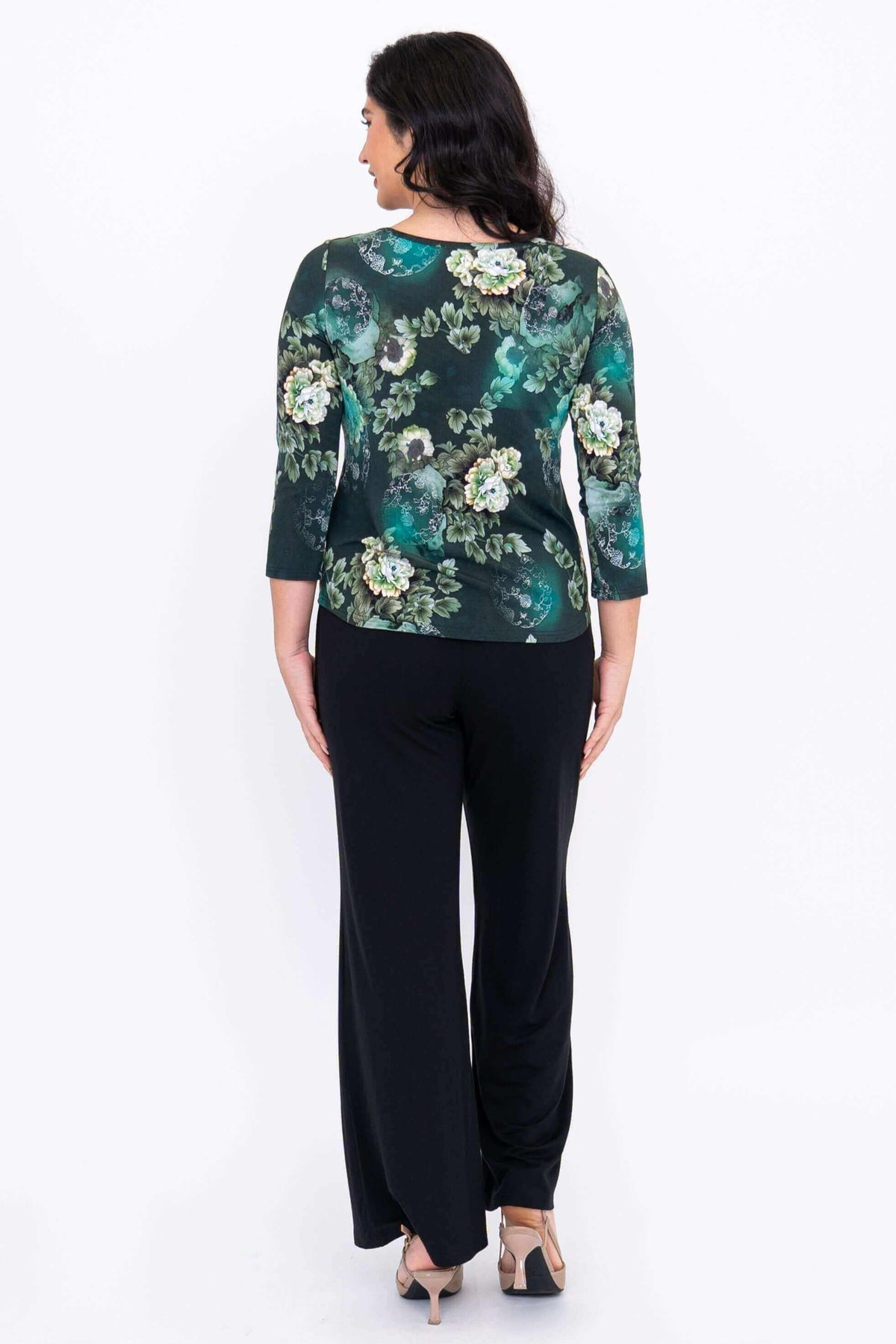 Back view of a woman wearing the green floral 3/4 sleeve top and black pants