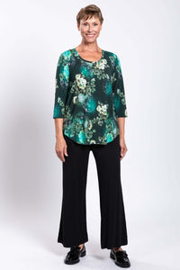 Woman standing in a green floral bamboo 3/4 sleeve top with black wide-leg pants