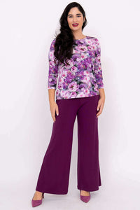 Woman posing in purple floral 3/4 sleeve top and purple pants