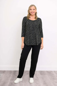 Blonde woman smiling in black polka dot bamboo 3/4 sleeve top and white sneakers