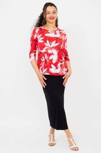 Model standing in a red floral 3/4 sleeve top paired with a long black skirt and white sandals
