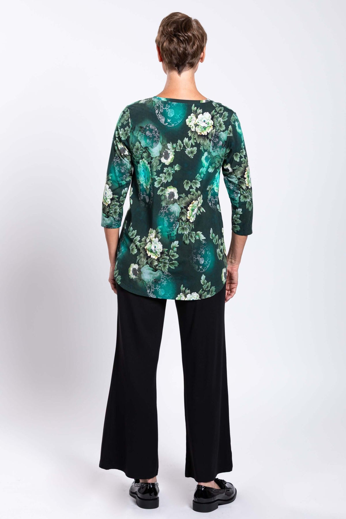Back view of a woman modeling the green floral bamboo 3/4 sleeve top