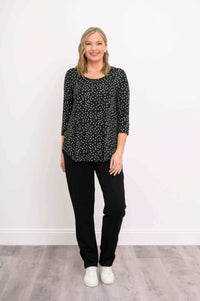 Woman in black polka dot 3/4 sleeve top standing straight with hands at sides