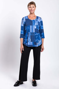 Front view of woman in blue mosaic 3/4 sleeve top and black pants