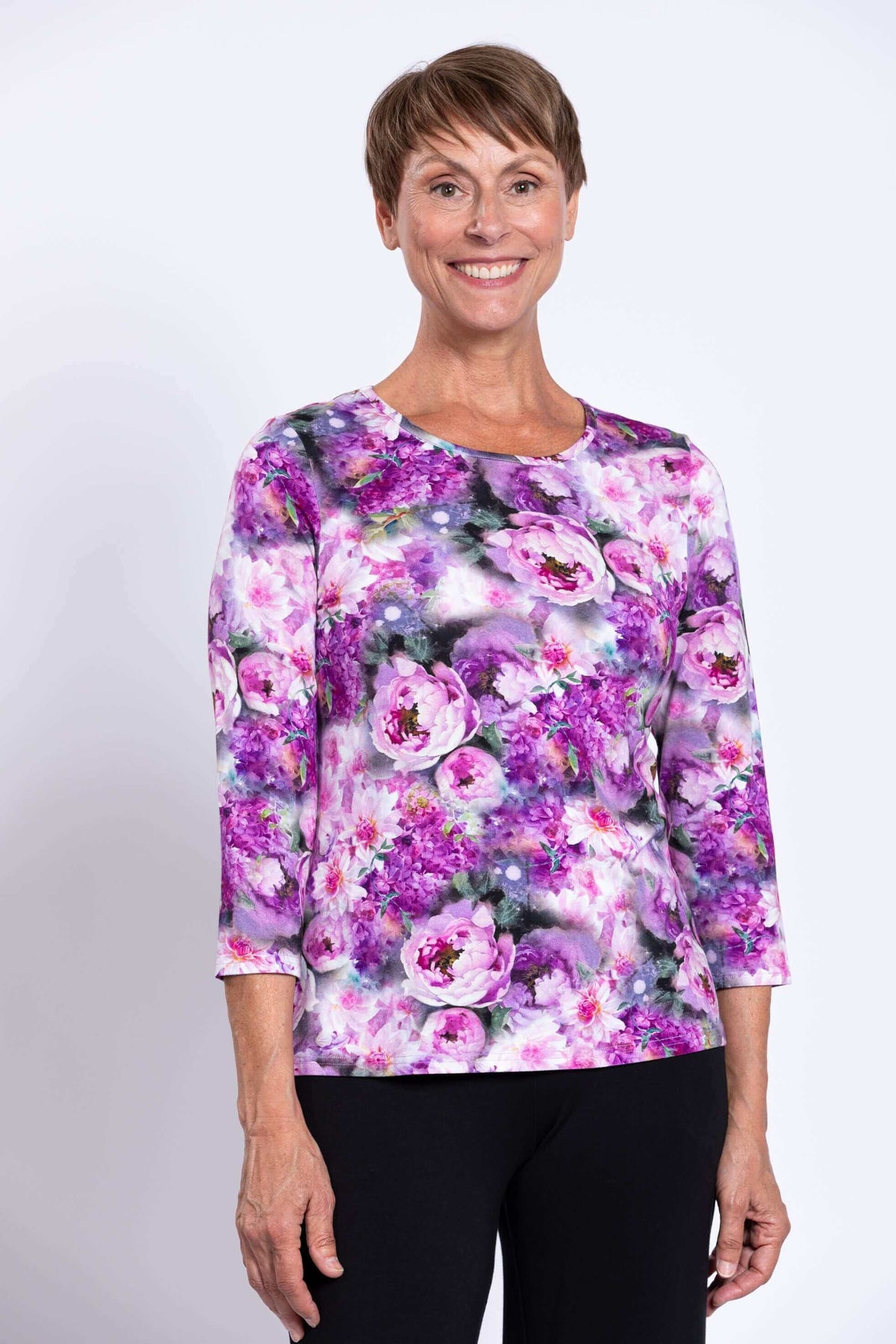 Woman wearing a purple floral 3/4 sleeve top with black pants