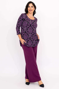 Side view of woman in purple damask Jazz 3/4 sleeve top and purple pants, hand in pocket
