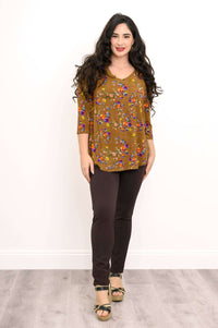 Woman standing in brown floral 3/4 sleeve top with slim pants and wedges