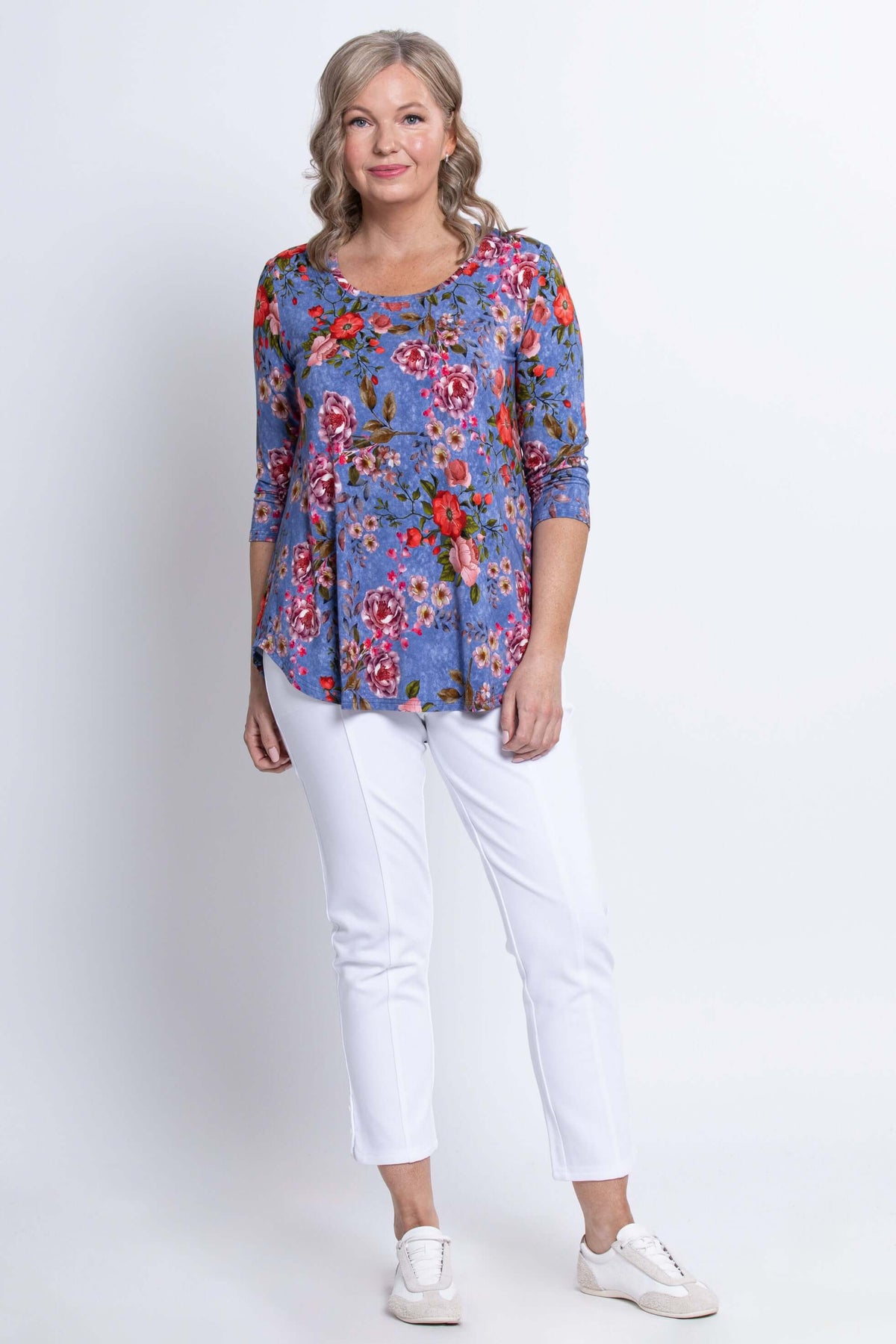 Full body shot of woman in blue floral bamboo 3/4 sleeve top and white pants