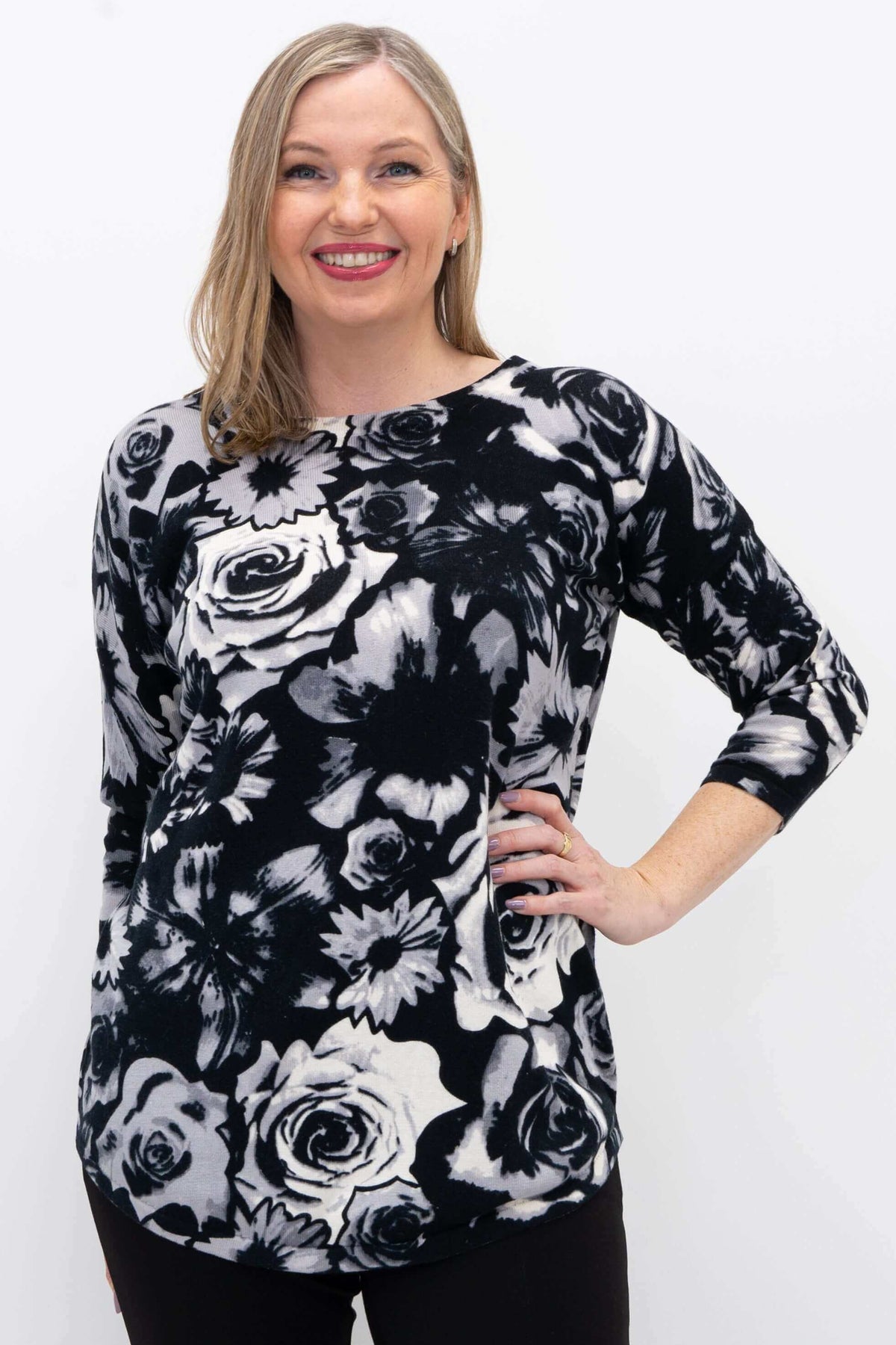Woman wearing a black and white floral pullover sweater with 3/4 sleeves, smiling