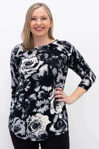 Woman wearing a black and white floral pullover sweater with 3/4 sleeves, smiling