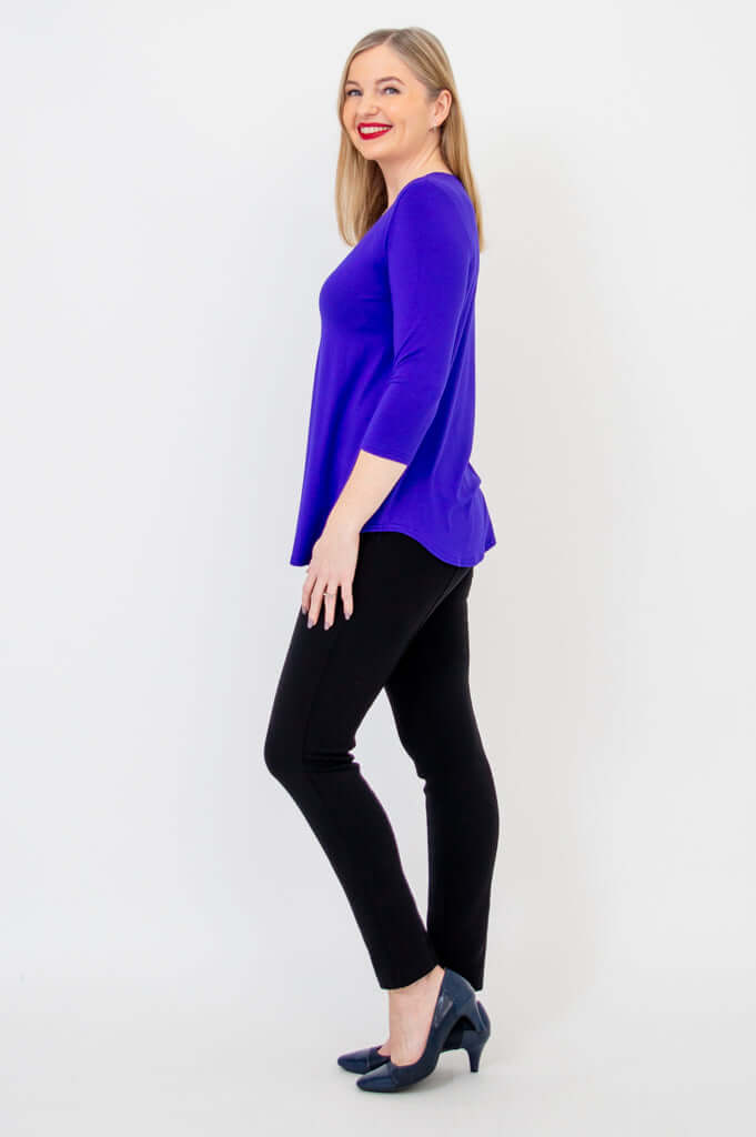 Side view of woman in purple V-neck bamboo top with 3/4 sleeves and black pants