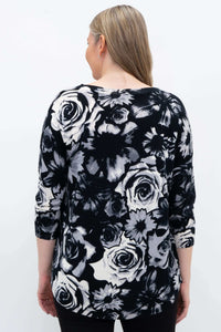 Back view of a woman in a black and white floral pullover sweater showing rounded hem