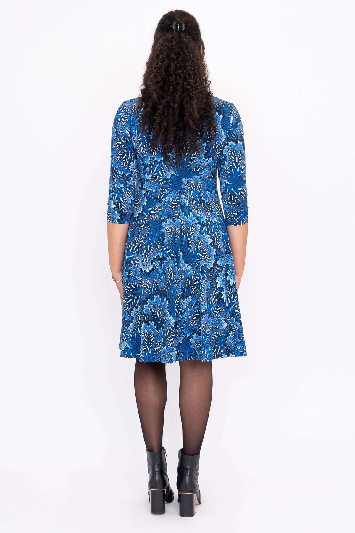 Back view of woman showing the blue floral fit and flare dress and black ankle boots