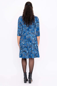 Back view of woman showing the blue floral fit and flare dress and black ankle boots
