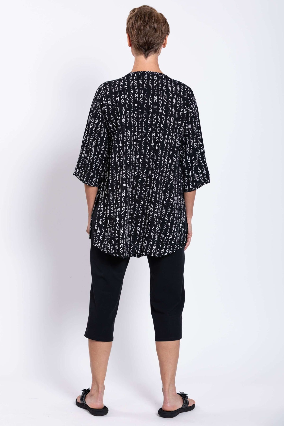 Back view of a woman wearing a black Batik blouse with white print and 3/4 sleeves