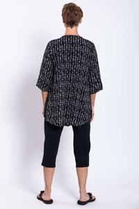 Back view of a woman wearing a black Batik blouse with white print and 3/4 sleeves