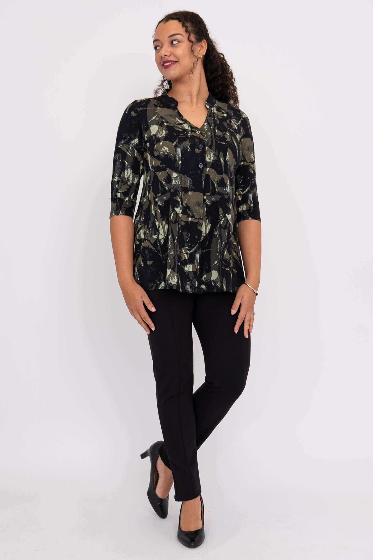 Woman in abstract print bamboo top with hands at sides, looking to the side